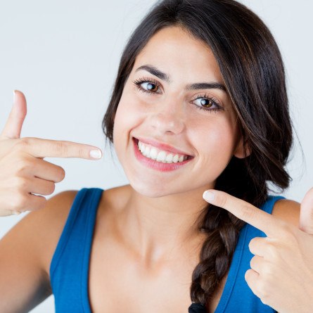 woman smiling and pointing to her teeth