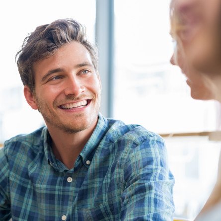 man smiling while talking to friend